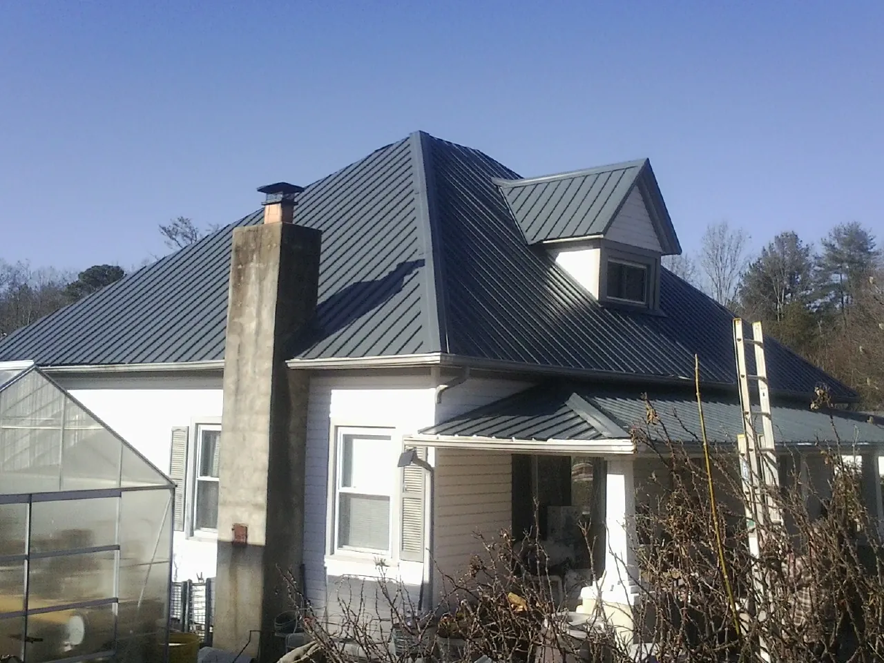 Dark blue standing seam metal roof on a white farmhouse with dormer — Slate & Tile Roof Repair by Roofing Brothers in Valencia
